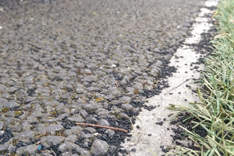 Photo of the edge of an artificial pitch, showing microplastic infill spilling off the pitch into the surrounding ground.